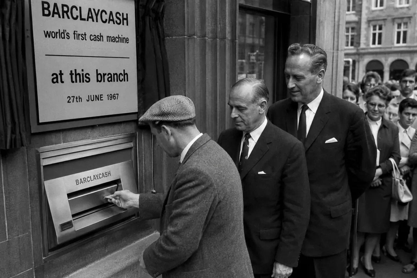 A man withdraws cash from Barclaycash, the world's first cash machine, at its 1967 unveiling as onlookers watch.